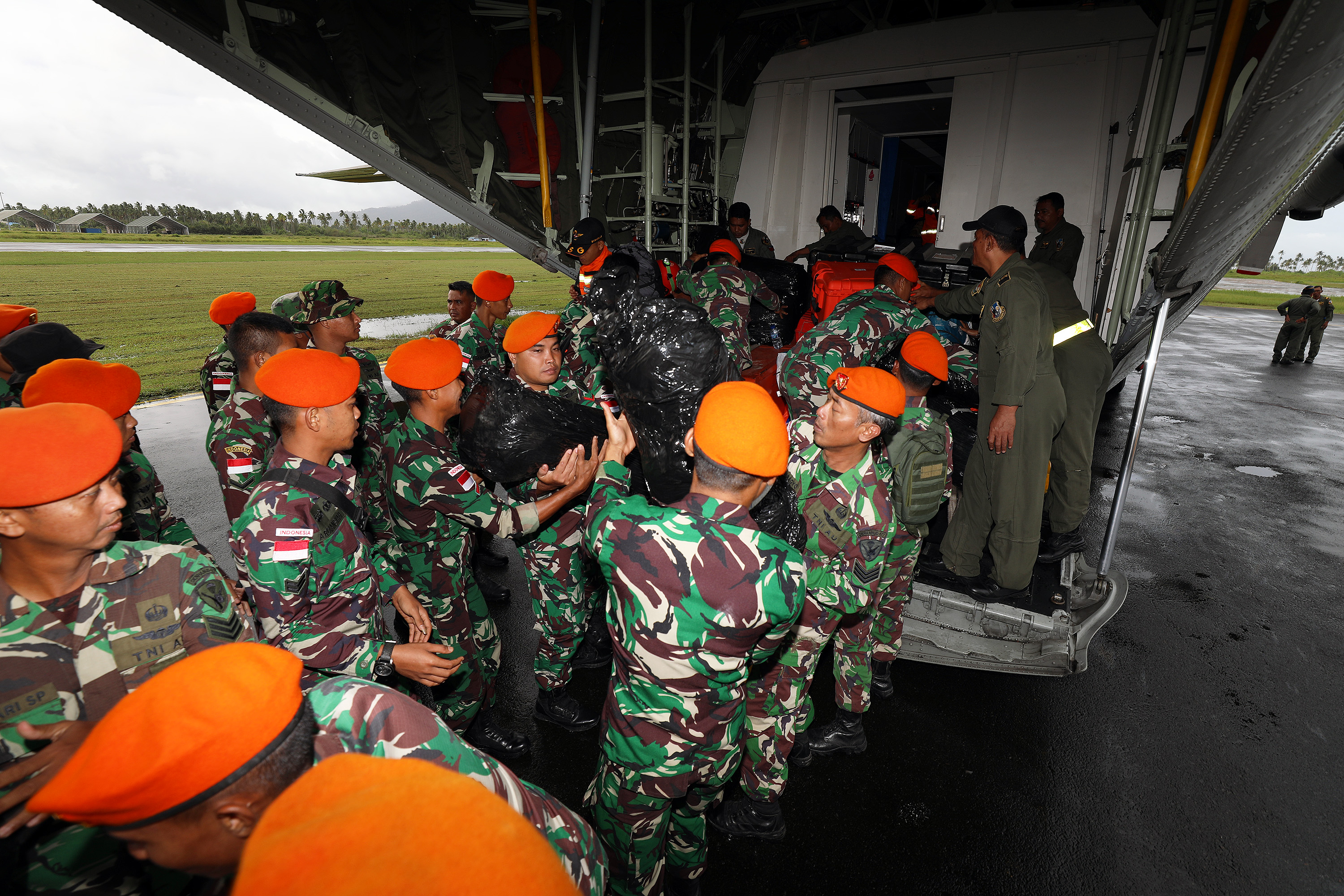 Anggota Kopasgat TNI AU menurunkan logistik dan peralatan BNPB dari pesawat Hercules C-130 sesaat setelah tiba di Lanud Raden Sadjad Ranai, Natuna, Selasa (7/3).